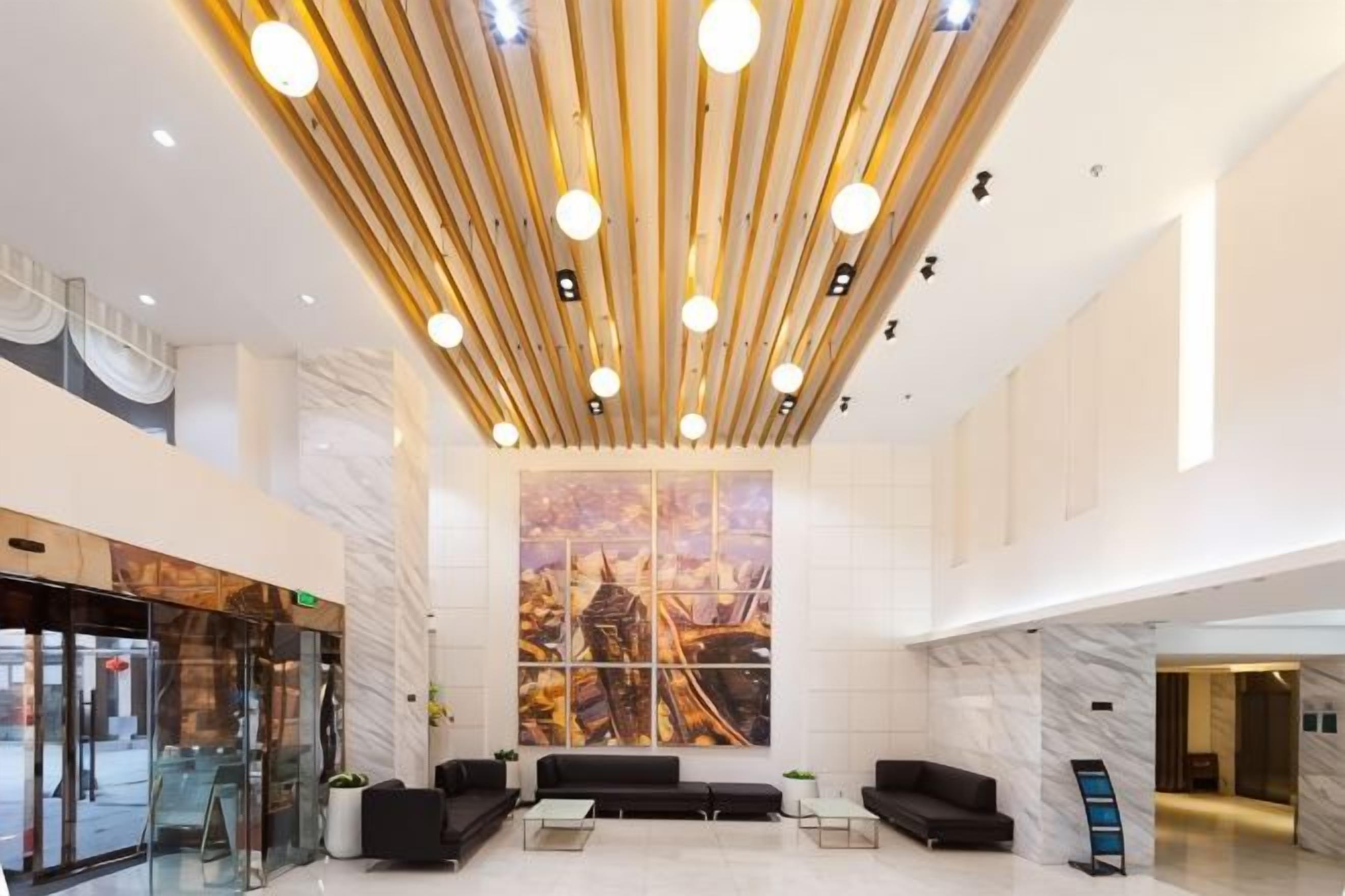 A modern lobby with a high ceiling, a large window with a cityscape view, and a reception desk.