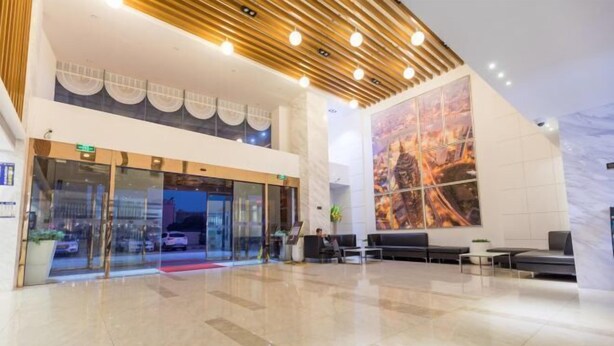 A modern hotel lobby with a glass entrance, a reception desk, seating area, and a large abstract mural. - Xinmi International Hotel (Shanghai Pudong International Airport Park Resort) (Shanghai)