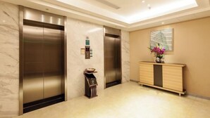 A modern elevator area with marble walls and a wooden console. - Xinmi International Hotel (Shanghai Pudong International Airport Park Resort) (Shanghai)