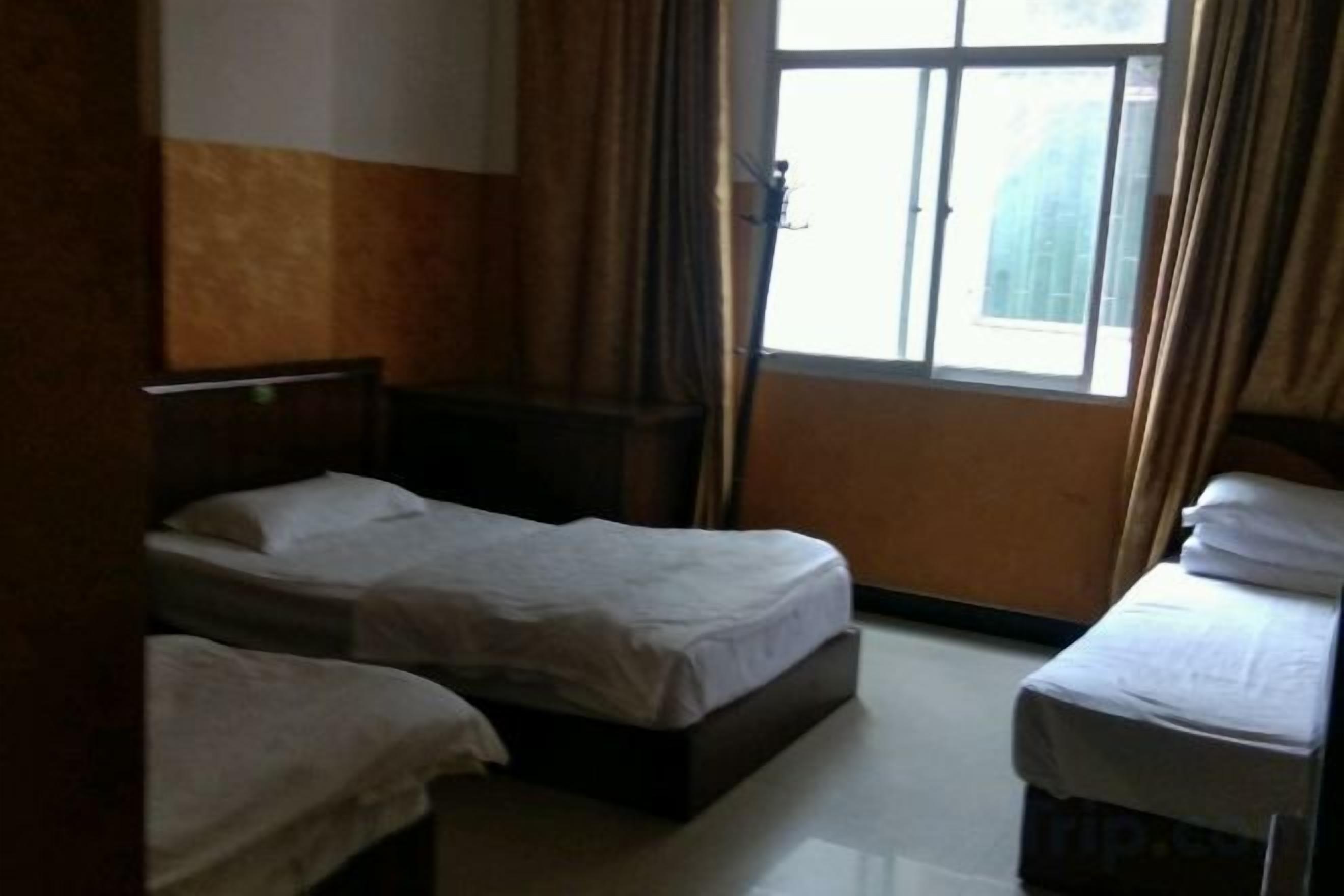 A room with two single beds, a window with curtains, and a door.