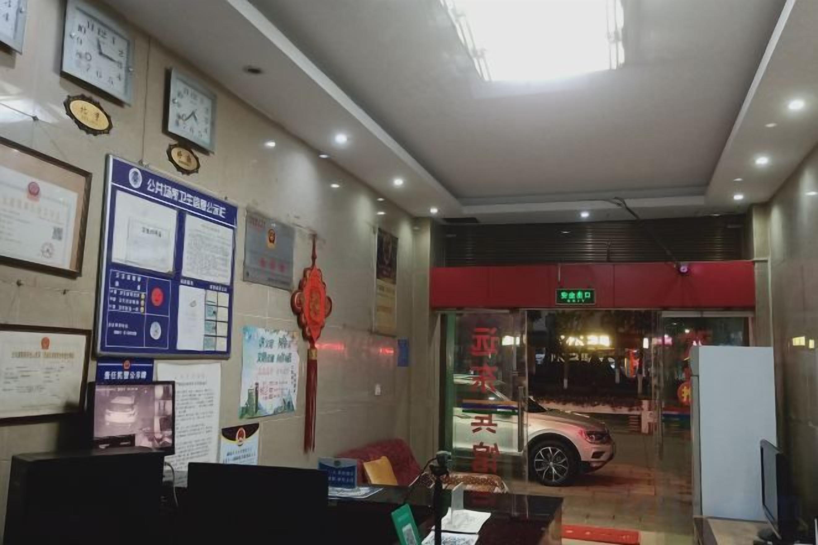 A reception area with a desk, chairs, and a counter. There are clocks on the wall and a sign above the counter.