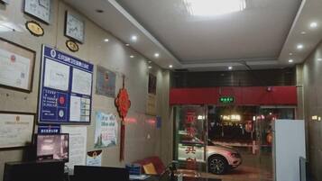 A reception area with a desk, chairs, and a counter. There are clocks on the wall and a sign above the counter.