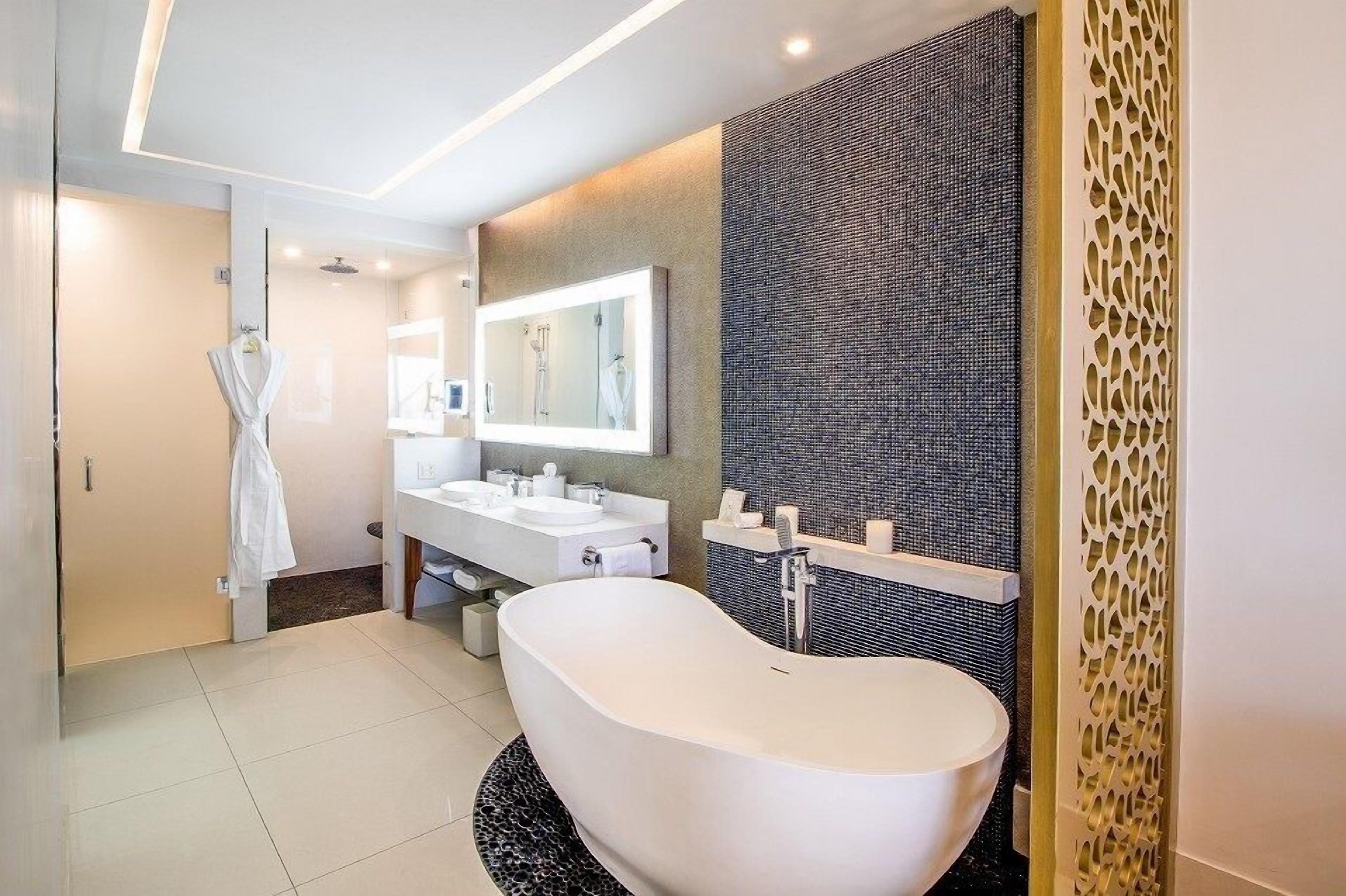 A modern bathroom with a freestanding bathtub, a large mirror, and a vanity with a sink and towel rack.