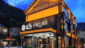 Un hotel con una entrada destacada y señalización, rodeado de un paisaje montañoso.