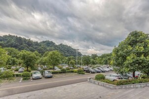 Un estacionamiento con coches y árboles, rodeado por un paisaje montañoso.