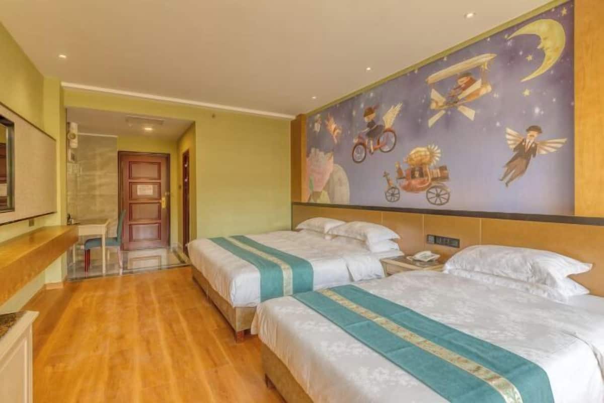 A hotel room with two beds, a wooden floor, a night sky mural, and a desk with a chair.
