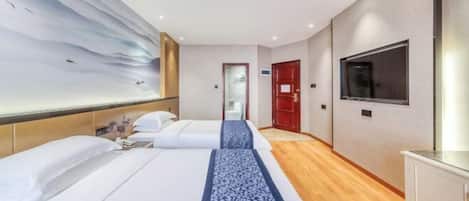A hotel room with two beds, a large wall mural, a TV, and a wooden floor.