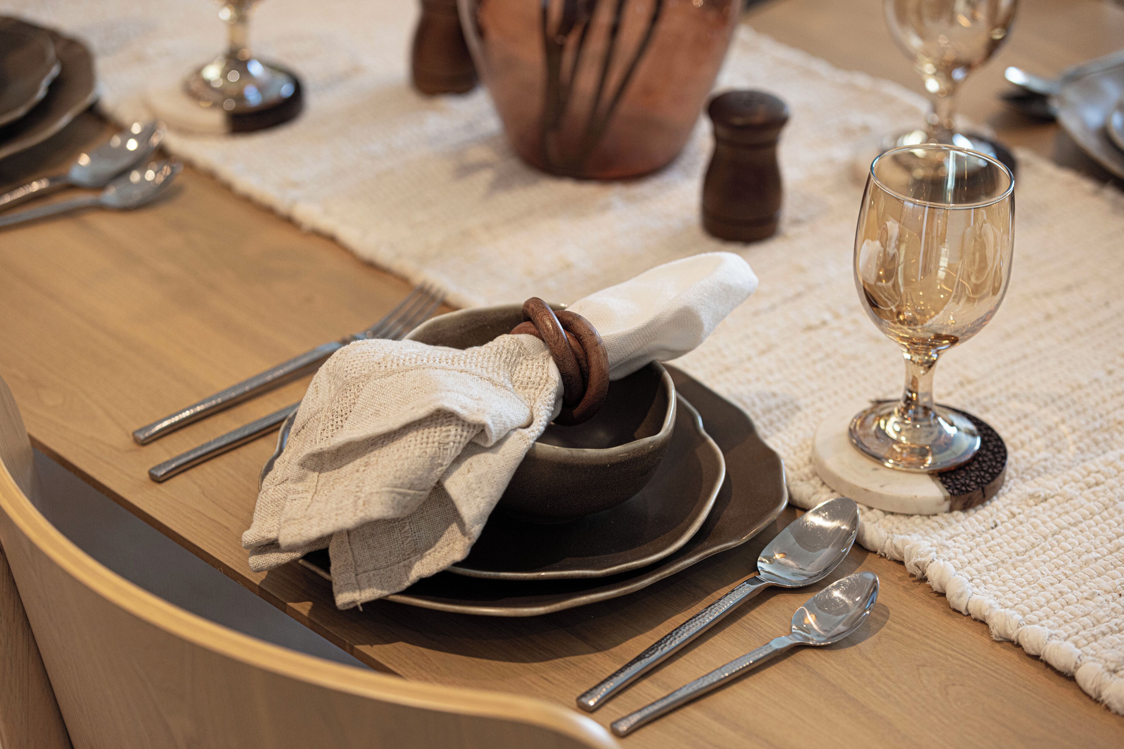 Une table à manger dressée avec des assiettes, des couverts, un bol, une serviette et un verre à vin.