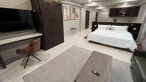 Une chambre d’hôtel moderne équipée d’un lit, d’un bureau, d’une télévision et d’une kitchenette.