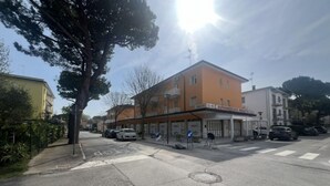 A street view with a building labeled "SUPERMERCATO PIAZZETTO" and parked cars. - Sunny Apartment With Balcony-beahost (San Michele al Tagliamento)