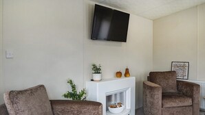 A living room with two sofas, a fireplace, a TV, and a radiator. - 3 bedroom accommodation in Carnaby, near Bridlington (Carnaby, near Bridlington)