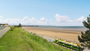 A coastal road with a green tram, grassy areas, and a beach. - 3 bedroom accommodation in Carnaby, near Bridlington (Carnaby, near Bridlington)