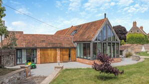 A modern house with a large glass extension, a wooden garage, and a well-maintained garden. - 4 bedroom accommodation in Middlezoy, near Bridgwater (Middlezoy, near Bridgwater)