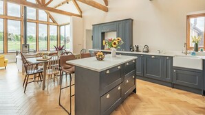 A spacious kitchen with dark grey cabinets, a central island, and large windows offering a view of the outdoors. - 4 bedroom accommodation in Middlezoy, near Bridgwater (Middlezoy, near Bridgwater)