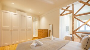 Ein Schlafzimmer mit einem großen Bett, einer hölzernen Kommode, einem Spiegel und einem Fenster mit Blick.