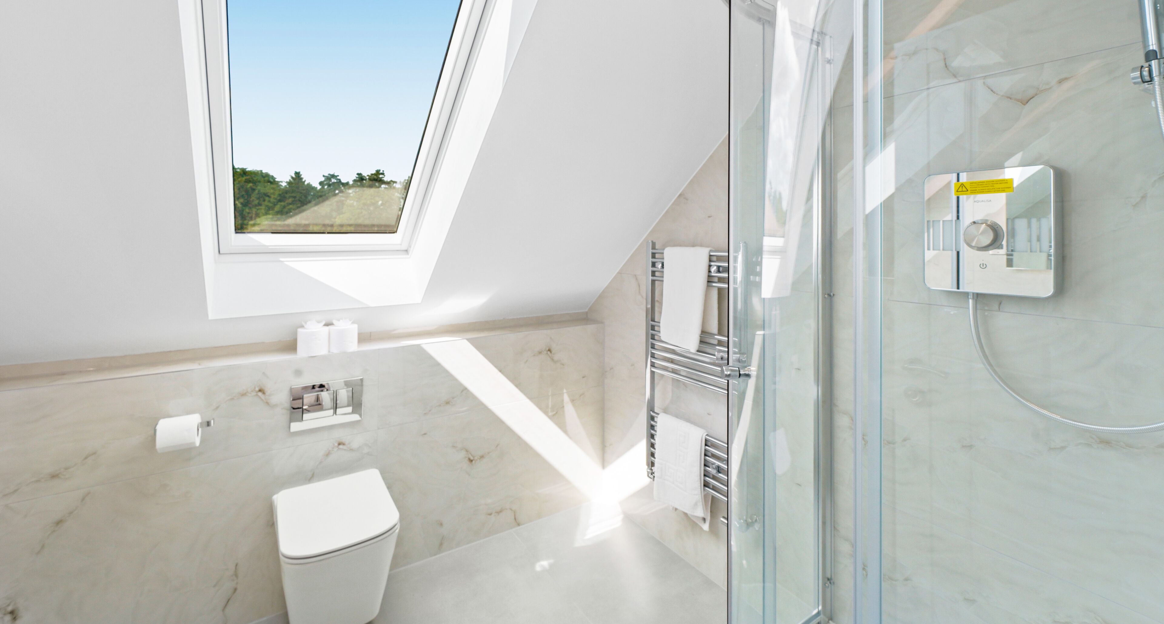 A modern bathroom with a skylight, a glass shower enclosure, and a toilet.