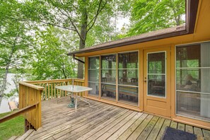 A wooden deck with a table and chairs, large windows, and a view of trees. - Sullivan Lake Cabin w/ Pierz & Hillman Access! (Pierz)