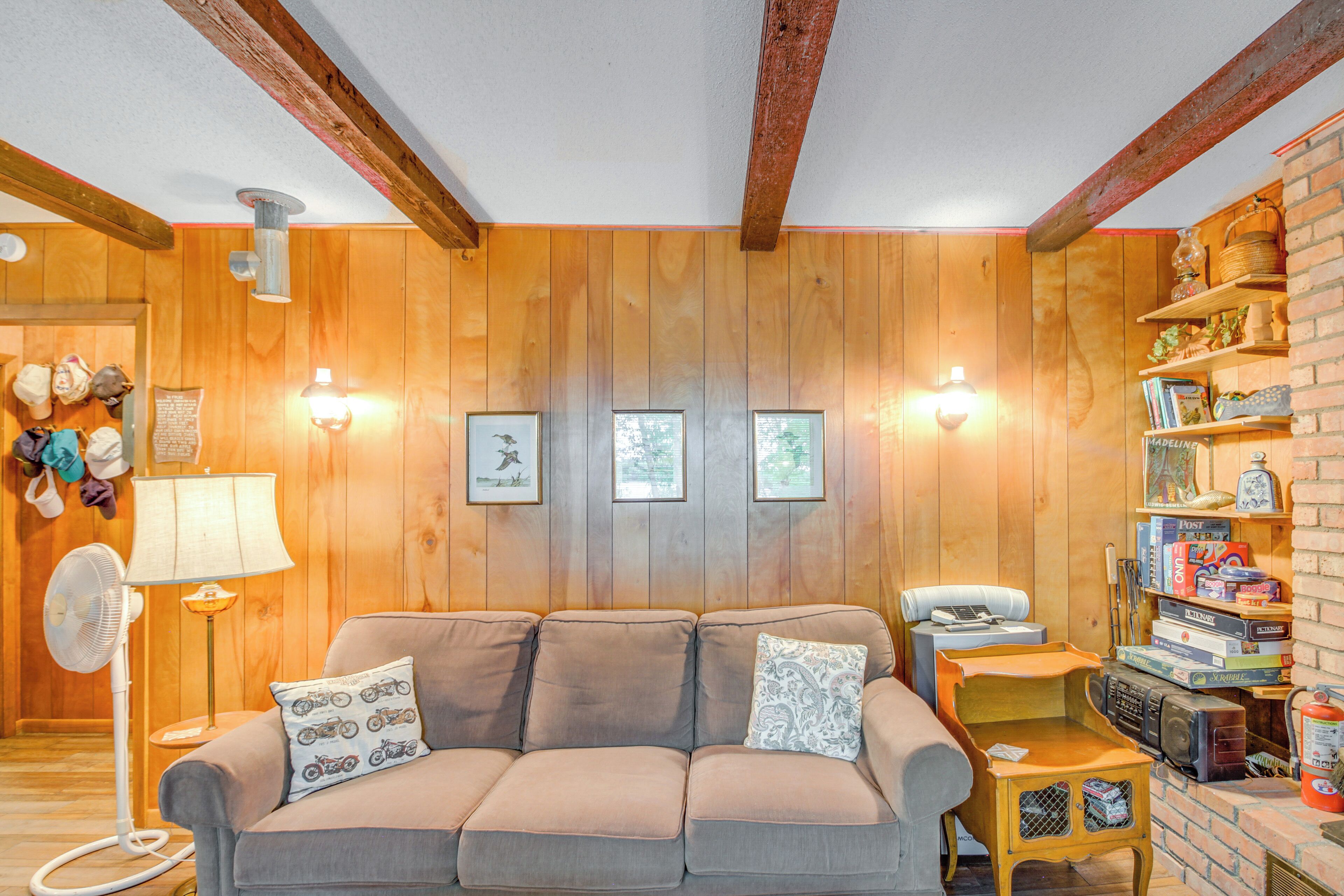 A cozy living room with a beige sofa, a small wooden table, and a brick wall with shelves.