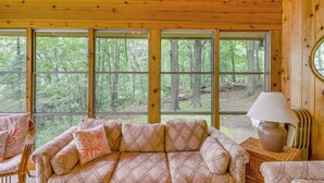 A cabin interior with a large window, a sofa, a chair, and a lamp. - Sullivan Lake Cabin w/ Pierz & Hillman Access! (Pierz)
