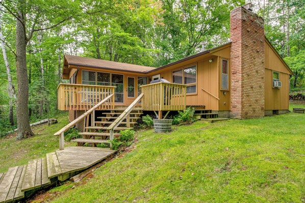 A cabin with a wooden deck, a chimney, and a staircase leading to the entrance. - Sullivan Lake Cabin w/ Pierz & Hillman Access! (Pierz)