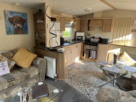 A compact living space with a kitchenette, a sofa, a coffee table, and a painting.