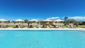A swimming pool with lounge chairs and umbrellas, surrounded by a stone wall and greenery. - Agriresort Masseria Giovanni - Tripla (Martano)