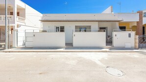Ein modernes Gebäude mit einem begrenzten Eingang, einem Balkon und blauem Himmel.