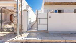Ein durch einen Zaun gesicherter Eingang zu einem Gebäude, mit einem Metallgitter und einer kleinen Treppe, die zu einer Tür führt.