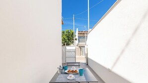 Ein kleiner Balkon mit Tisch für zwei Personen, einem Stuhl und Blick auf die Straße sowie die dahinterliegenden Gebäude.