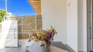 A room with a glass vase of dried flowers on a table, a white refrigerator, and a bamboo fence outside. - Residence Albeach - Bilo 3 (Porto Cesareo)