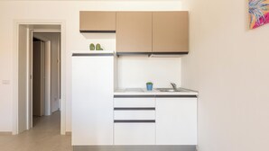 A modern kitchen with white cabinets, a stainless steel sink, and a small potted plant. - Residence Albeach - Bilo 3 (Porto Cesareo)