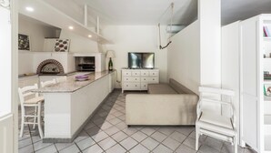 Una cocina compacta con isla integrada, muebles blancos y piso de baldosas.
