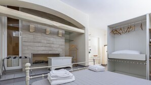 Un dormitorio moderno con cama, chimenea, armario y balcón con barandilla.