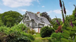 A Tudor-style house surrounded by lush greenery and flowering plants. - 6 bedroom accommodation in Okehampton (Okehampton)