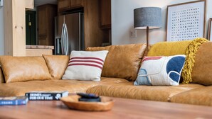 Una sala de estar acogedora con un sofá de cuero, una mesa de centro de madera y un control remoto.