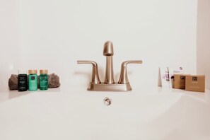 A bathroom sink with a modern faucet, a towel, and toiletries.