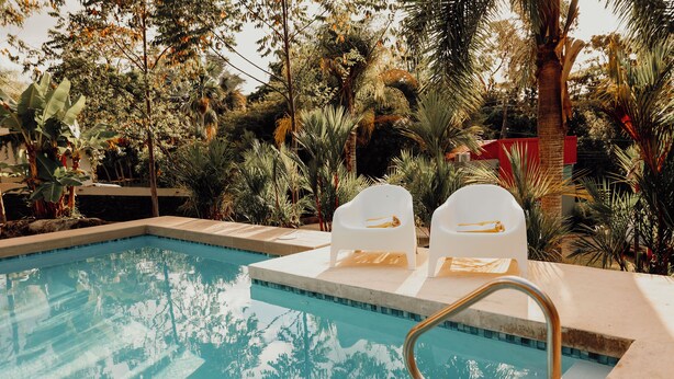 Une piscine avec deux chaises longues blanches et un escalier en métal.