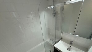 A modern bathroom with a glass-enclosed shower, a white sink, and a mirror. - Nice T2 with 2 balconies on the seafront (Ouistreham)