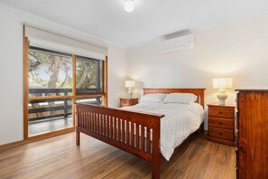 Relax in this serene retreat with a comfortable bed, a large window offering a view of the surrounding trees, and a convenient nightstand and dresser.