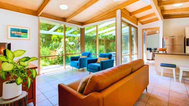 A modern interior with a wooden ceiling, large windows, a sofa, and a dining area. - Garden Cottage - Somers (Somers)
