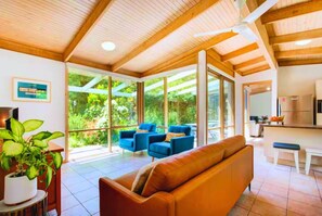 A modern interior with a wooden ceiling, large windows, a sofa, and a dining area. - Garden Cottage - Somers (Somers)