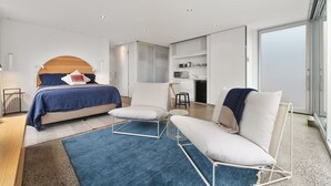 A modern hotel room with a bed, two sofas, a small table, and a kitchenette. - Couples Hillside Retreat (McCrae)