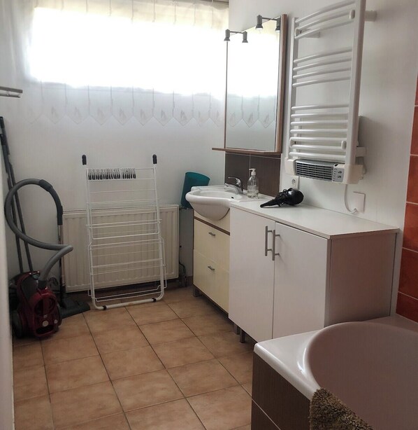 Une salle de bain avec un lavabo blanc, un miroir, un porte-serviettes, un radiateur et une douche.