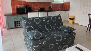 A compact living space with a kitchenette, a sofa with a circular pattern, and a small dining table.