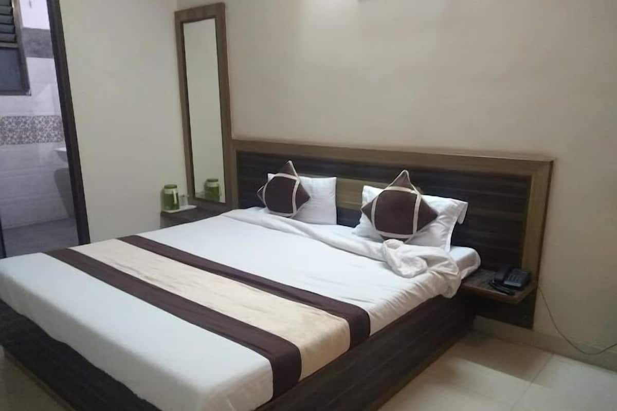 A neatly made bed with a striped bedspread, a wooden headboard, and a bedside table with a phone and a small lamp.