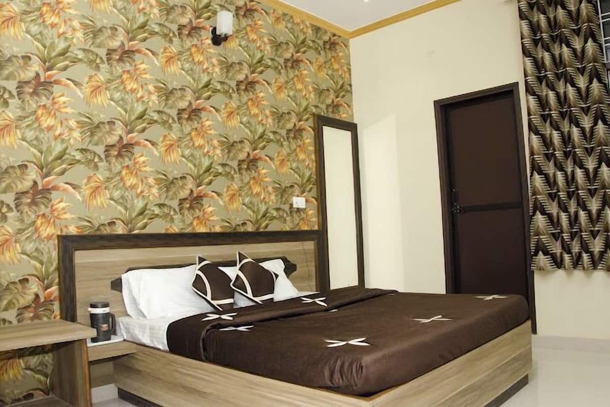 A neatly made bed with a brown bedspread and white pillows, a nightstand with a coffee cup, and a wall with a floral wallpaper pattern.