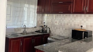 Una cocina moderna con armarios de madera oscura, encimera de granito, pileta de acero inoxidable y microondas.