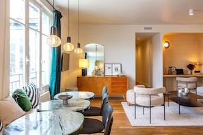 A modern living room with a marble coffee table, comfortable seating, and pendant lighting.