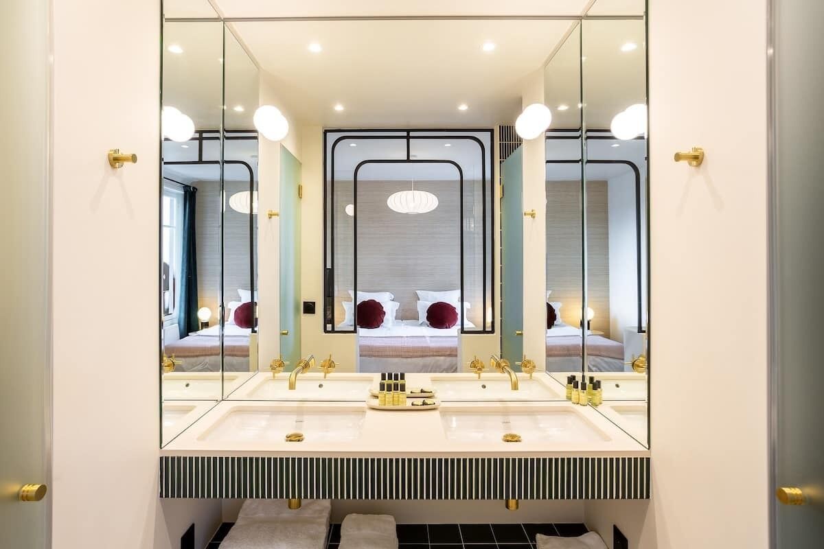 A modern bathroom with a large mirror, dual sinks, and a towel rack.