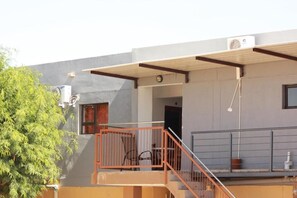 A building with a grey facade, a wooden staircase, and an air conditioning unit.
